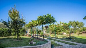 A garden with a stone pathway, potted plants, and a pergola structure. - Adriana by Interhome (Pula)