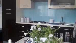 A kitchen with a stove, sink, and cabinets. There is a white flower vase on the table. - VILLASIMIUS CENTRO HOLIDAY HOUSE (Villasimius)