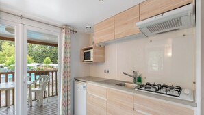 Una cucina moderna con mobili in legno, forno a microonde integrato, piano cottura a gas e lavello.