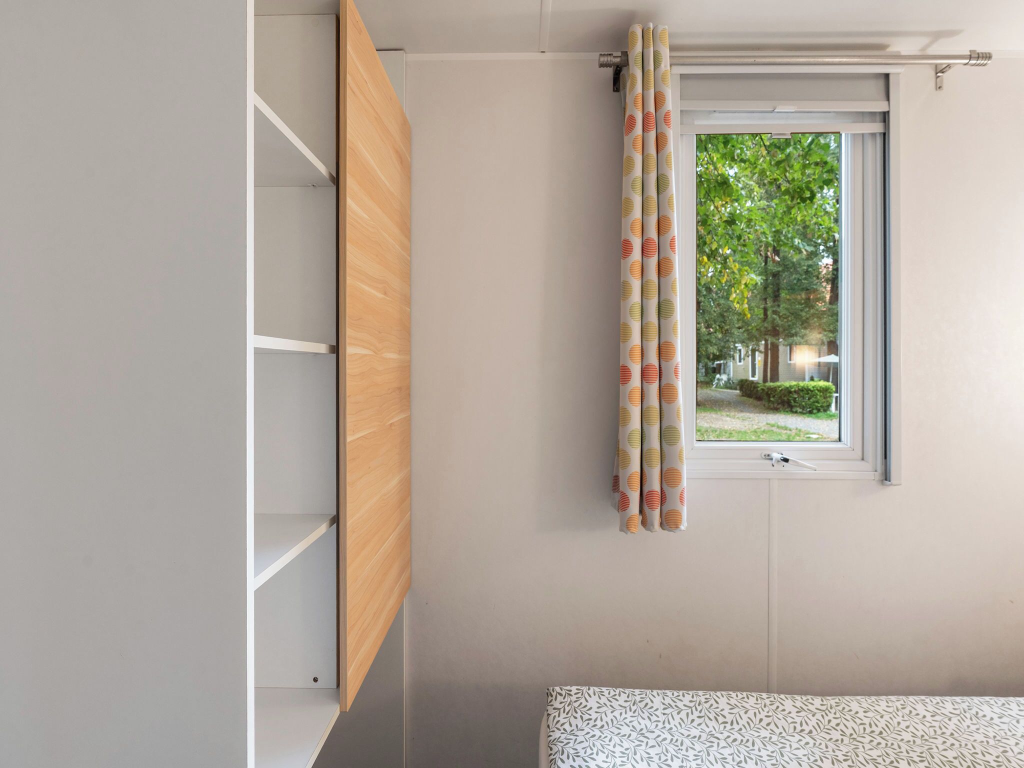 A room with a window, a wooden cabinet, and a patterned curtain.