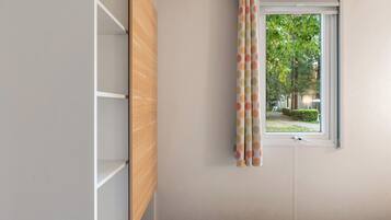 A room with a window, a wooden cabinet, and a patterned curtain.