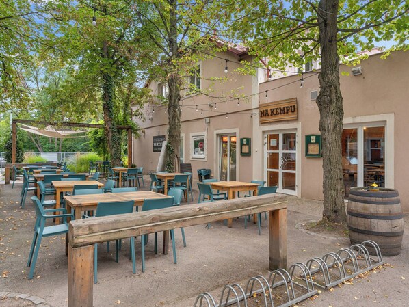An outdoor seating area with tables and chairs, a wooden bench, and a barrel.