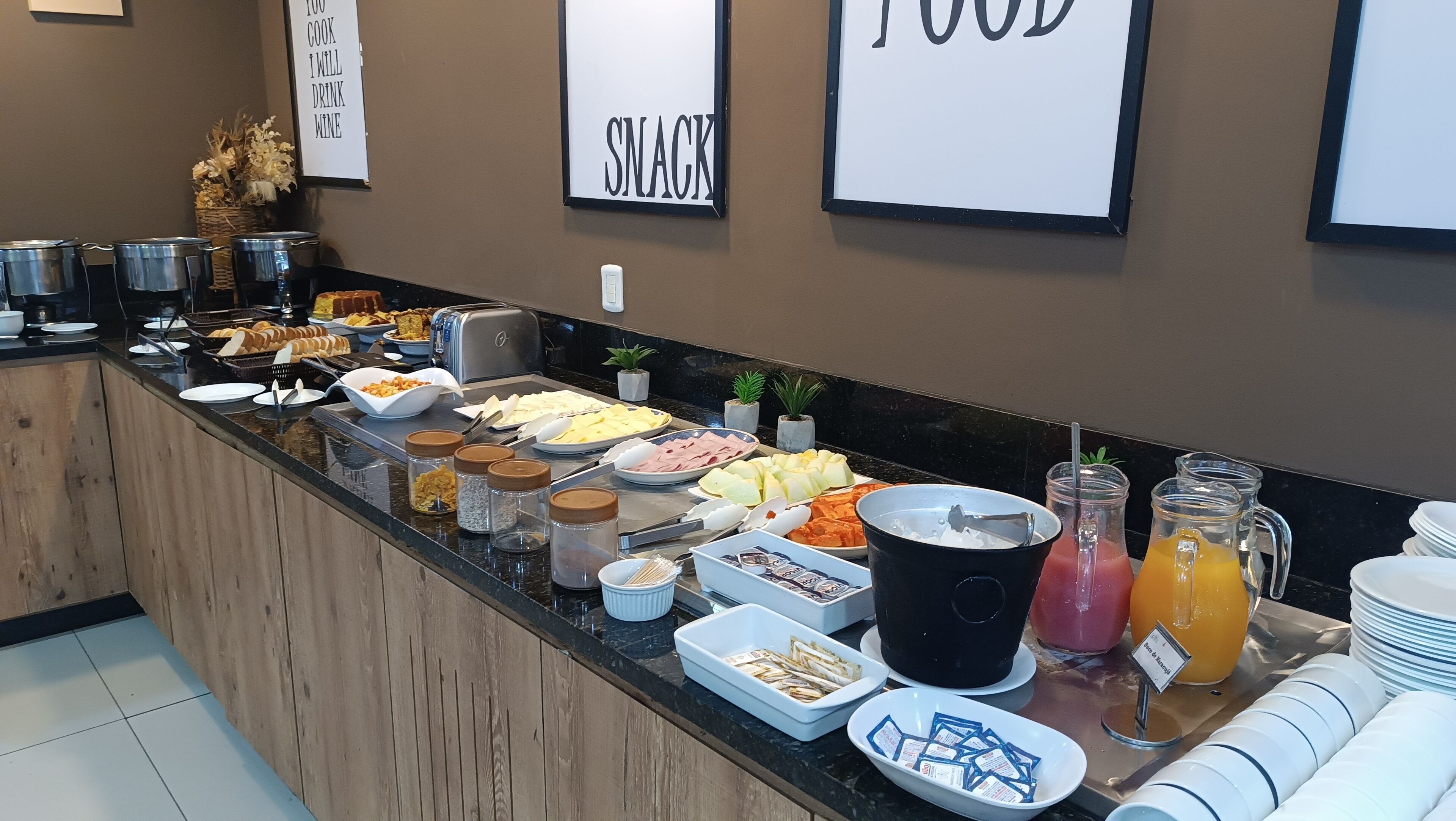 Mostrador de buffet con diversos alimentos y una estación de zumos.