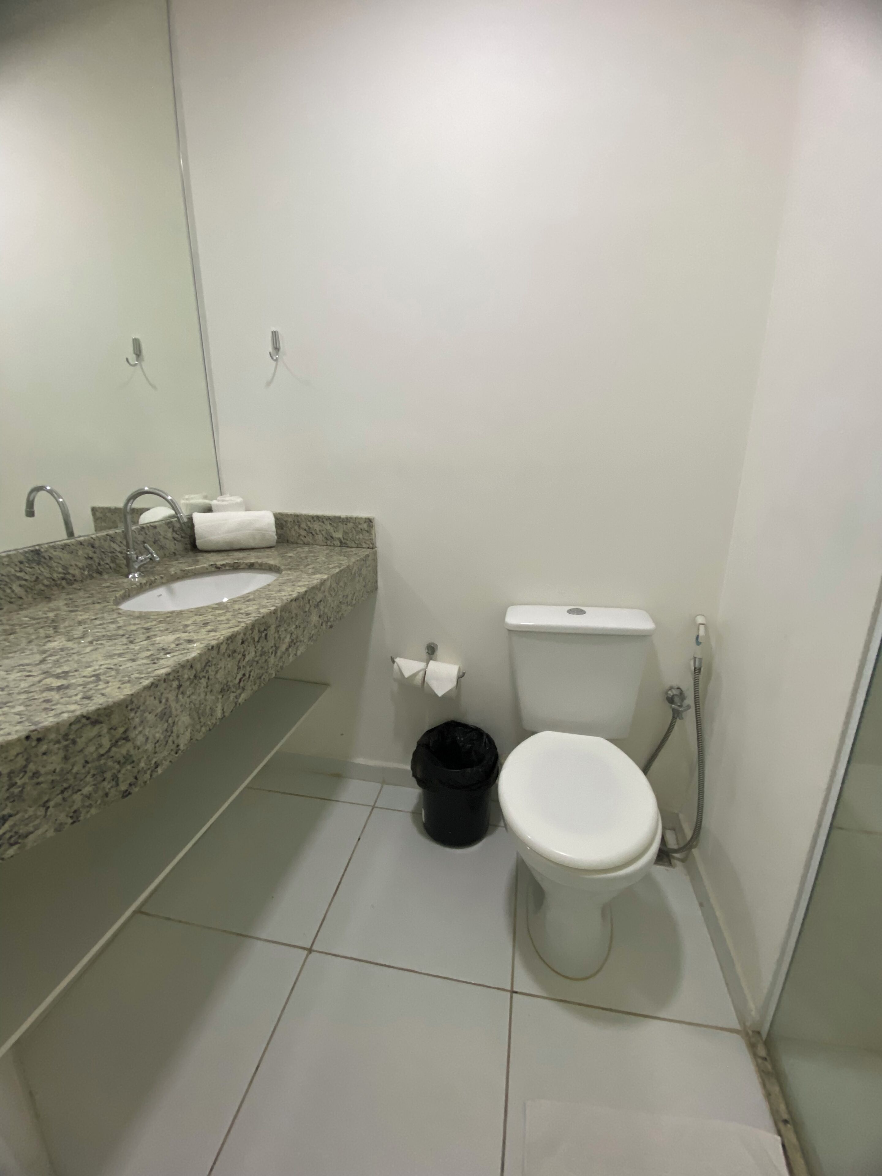 Een badkamer met een wastafel met granieten blad, toilet en douche.