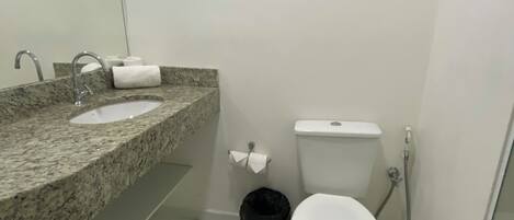 Een badkamer met een wastafel met granieten blad, toilet en douche.