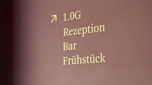 Eine Treppe mit einem Schild, das den Weg zur 1.0G Rezeption Bar und Frühstück anzeigt.
