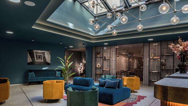 Ein moderner Lounge-Bereich mit einem blauen Sofagarnitur, gelben Sesseln und einem zentralen Couchtisch.