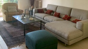 A living room with a sofa, armchair, glass coffee table, and a green ottoman. - Beautiful Provencal villa of charm with beautiful views of village and castle (Villeneuve-Loubet)