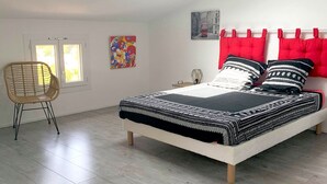 A bedroom with a skylight, a bed with red headboard pillows, a chair, and a colorful abstract painting. - Beautiful Provencal villa of charm with beautiful views of village and castle (Villeneuve-Loubet)