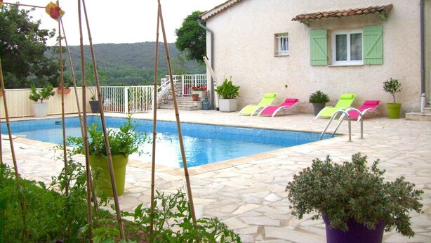 A swimming pool area with a stone patio, a house with green shutters, and several lounge chairs. - Beautiful Provencal villa of charm with beautiful views of village and castle (Villeneuve-Loubet)