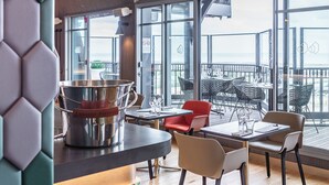 Un espace de restauration moderne offrant une vue sur la ville, de grandes fenêtres et un mobilier contemporain.