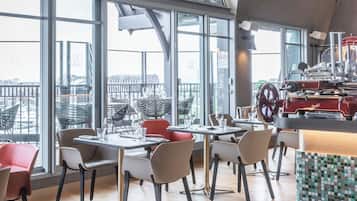 A modern restaurant with a high ceiling, large windows, and a central bar area.