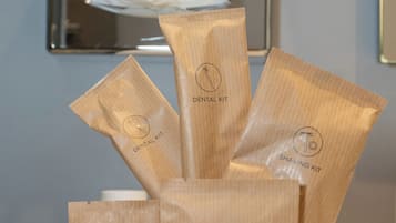 Una presentación de bolsas de tocador de madera con etiquetas como "Dental Kit", "Shaving Kit", "Hower Cap" y "Vanity Kit" sobre una superficie blanca.