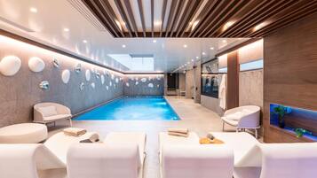 Un área interior de piscina moderna con vista despejada, asientos y una pared de madera con una planta.