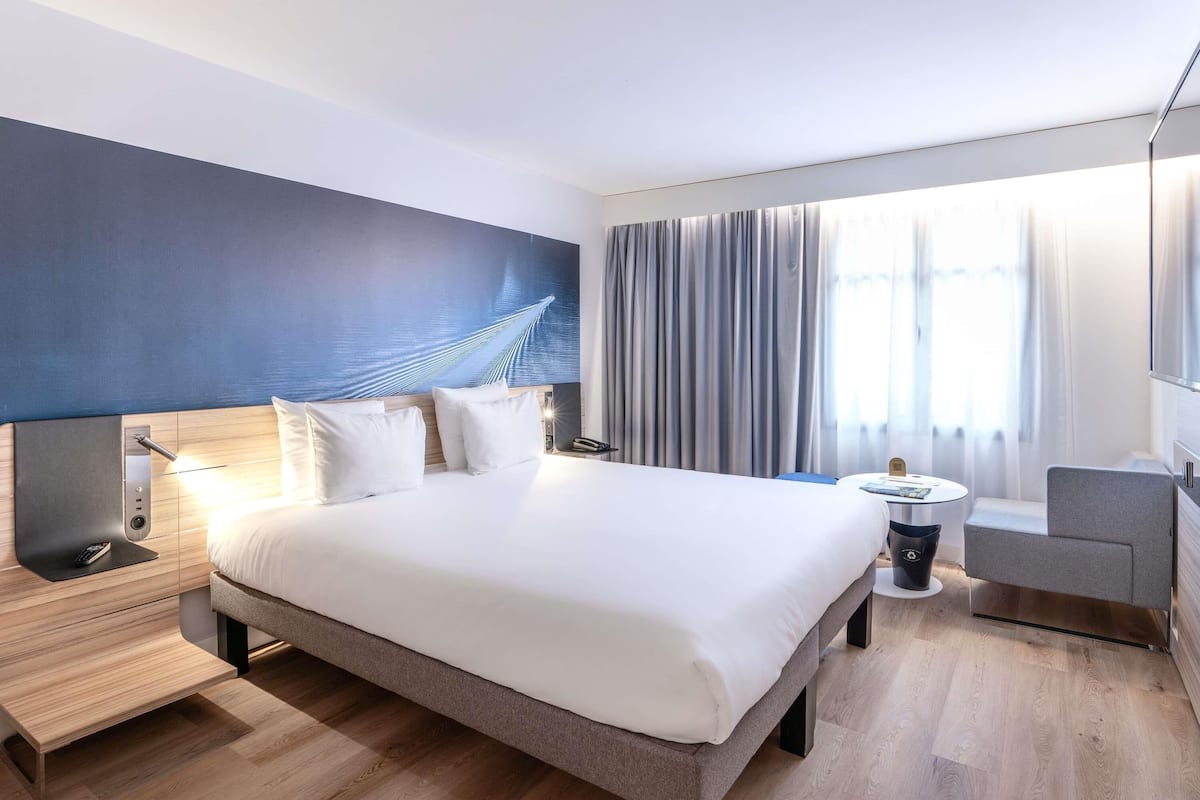 Una habitación de hotel moderna con una cama grande, mesitas de noche, un escritorio y una silla.