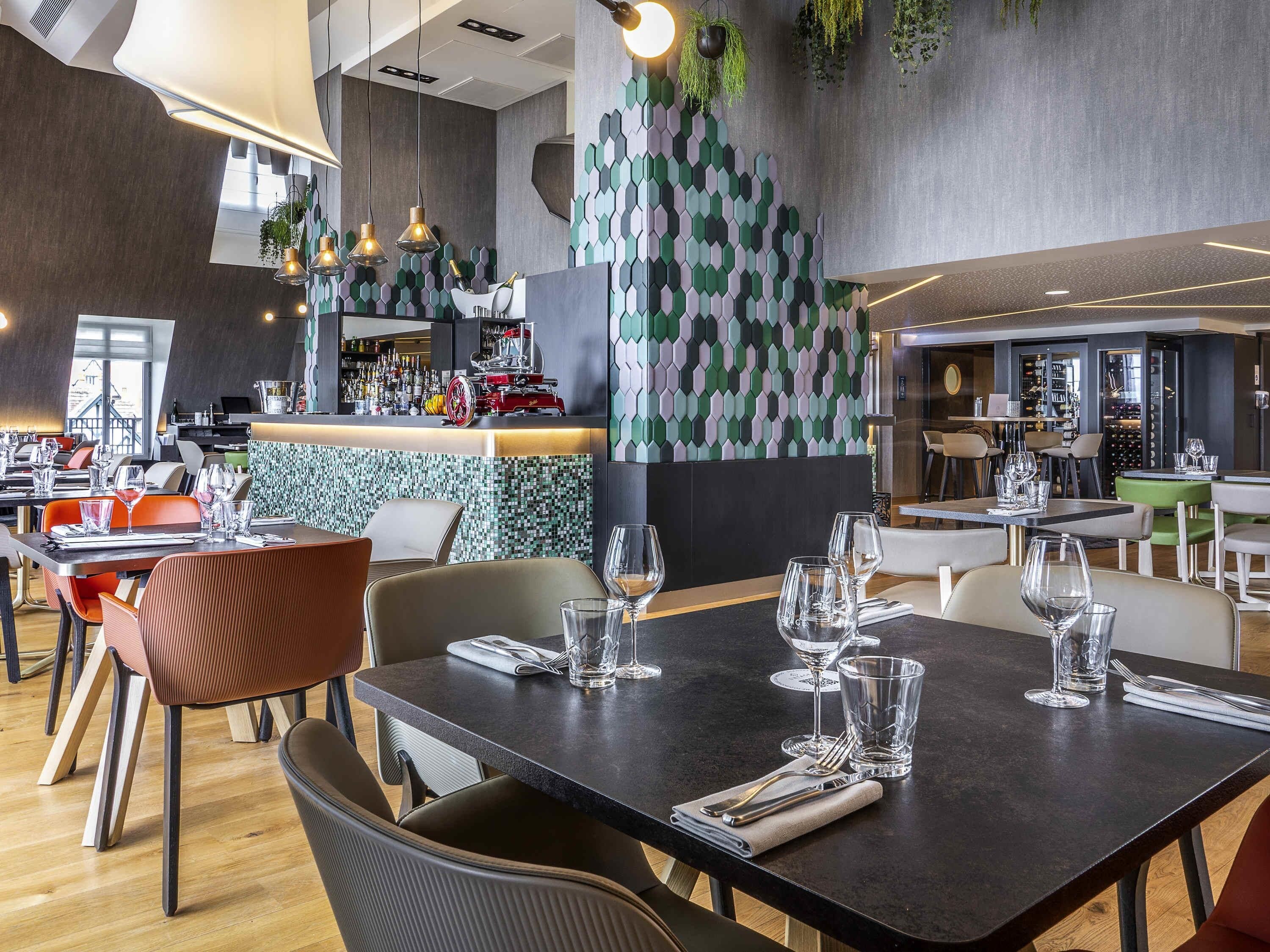 Ein modernes Restaurant mit Bar, Esstischen und Stühlen.