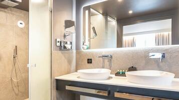 Une salle de bain moderne avec deux lavabos, un grand miroir et une douche.