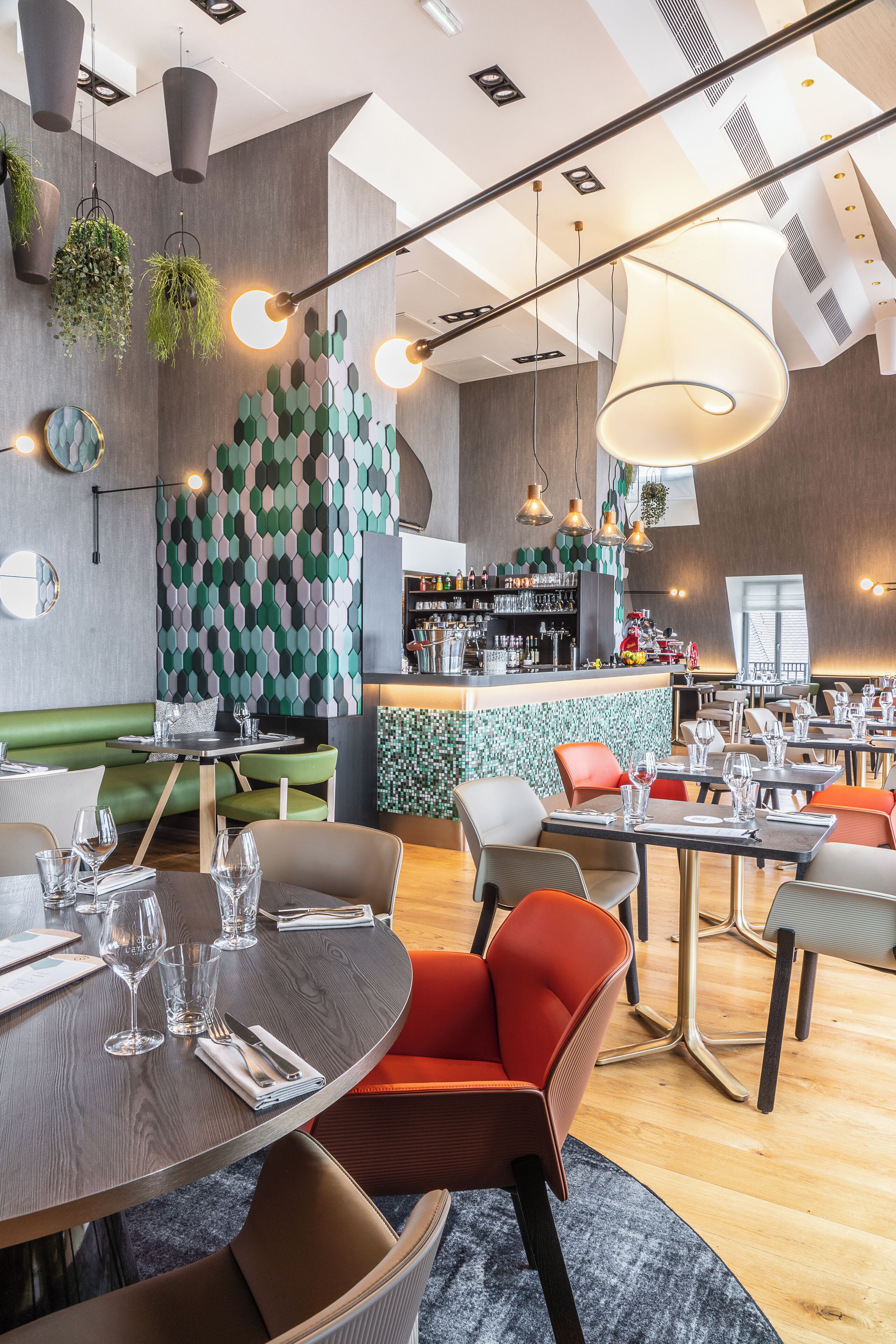 A modern restaurant with a bar area, green patterned wall, and various seating options.