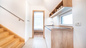 Eine moderne Küche mit Holzschränken, einem eingebauten Herd und einem Fenster über der Spüle.
