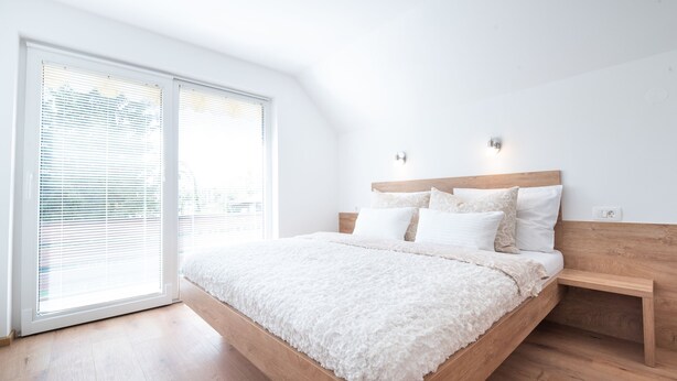 Ein Schlafzimmer mit einem Bettgestell aus Holz, weißer Bettwäsche und einem kleinen Nachttisch.