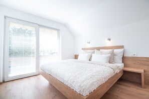 Ein Schlafzimmer mit einem Bettgestell aus Holz, weißer Bettwäsche und einem kleinen Nachttisch.