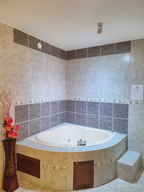 A modern bathroom with a freestanding bathtub, tiled walls, and a decorative vase with flowers. - Hotel Misky Samay (Ayacucho)
