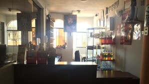 A room with a large window, a counter with various items, and a shelf with bottled drinks. - Hotel Misky Samay (Ayacucho)