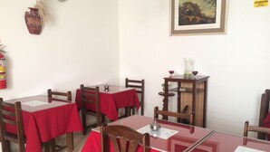 A dining area with tables covered in red tablecloths, wooden chairs, and a small wooden cabinet with glassware. - Hotel Misky Samay (Ayacucho)