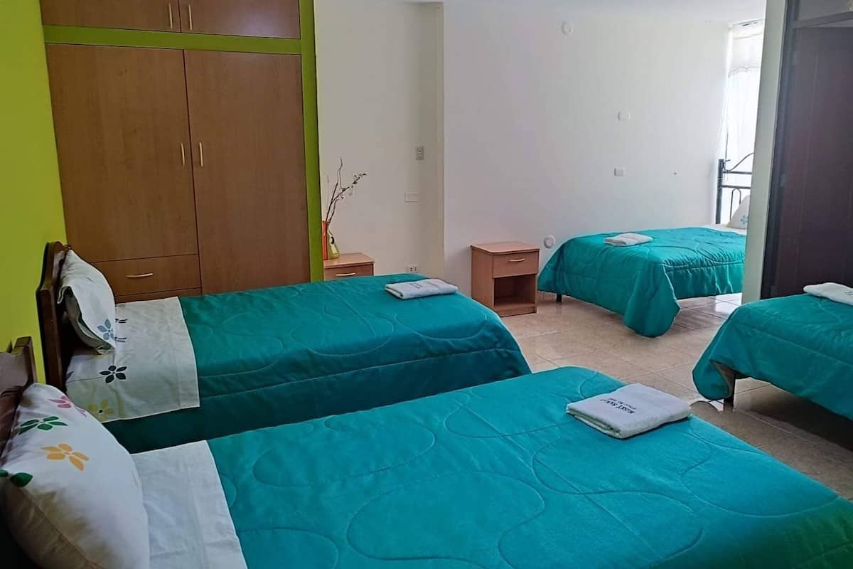 A hotel room with two beds, a wardrobe, a small table, and a window.