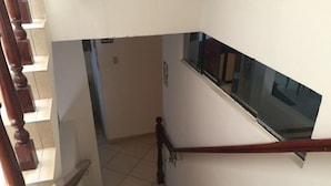 A staircase with a wooden handrail and a glass window on the right. - Hotel Misky Samay (Ayacucho)