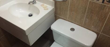 A bathroom with a sink, toilet, and a small shelf with soap.