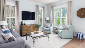 Un salon moderne comprenant un canapé, un fauteuil, une table basse et un téléviseur.