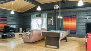 Een gezellige kamer met een pooltafel, een leren bank en een televisie.