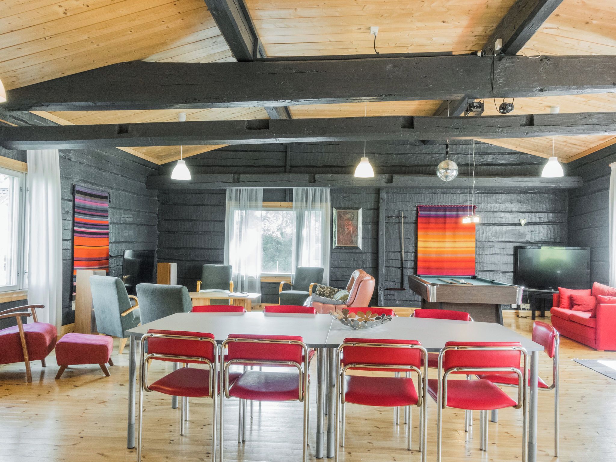 A modern interior with a dining area, red chairs, and a television.