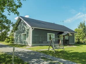 A single-story house with a sloped roof, a front porch, and a swing set.