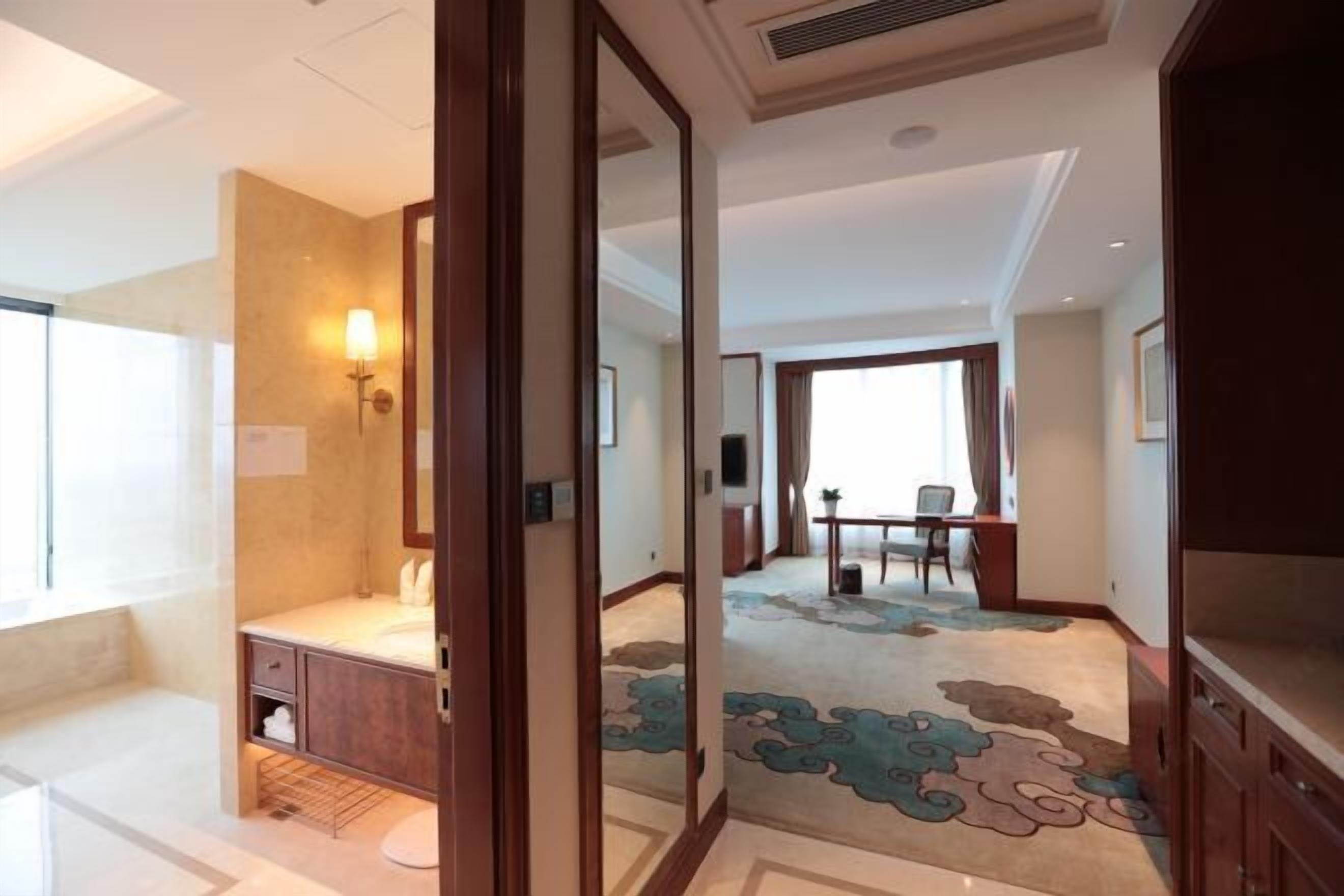 Quarto de hotel com banheiro, área de refeições e sala de estar.