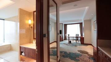 Quarto de hotel com banheiro, área de refeições e sala de estar.