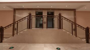 Una imponente escalera con barandilla de madera y puertas de vidrio en la parte superior.