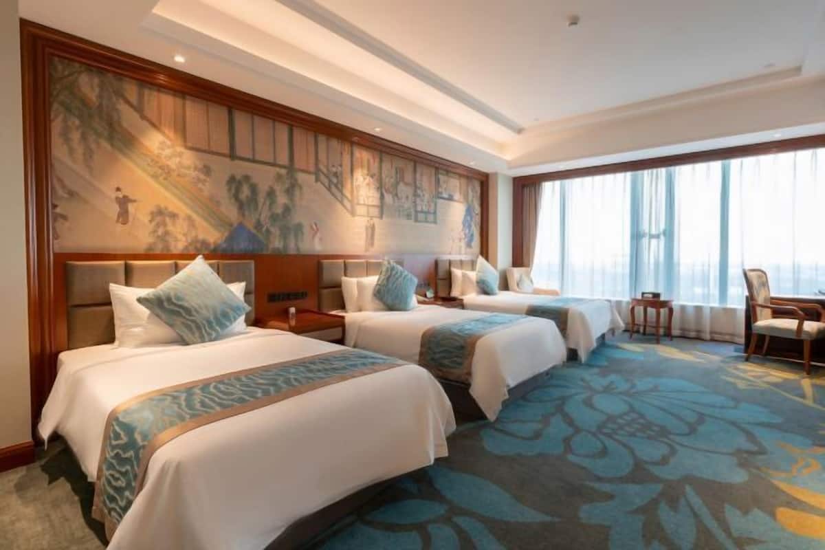 Habitación de hotel con dos camas, un mural grande en la pared y vista a la ciudad.