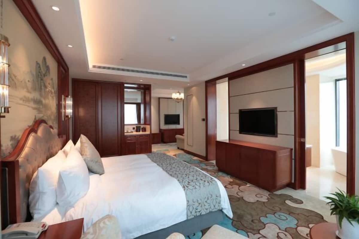 Una habitación de hotel con una cama grande, televisión, escritorio y baño.