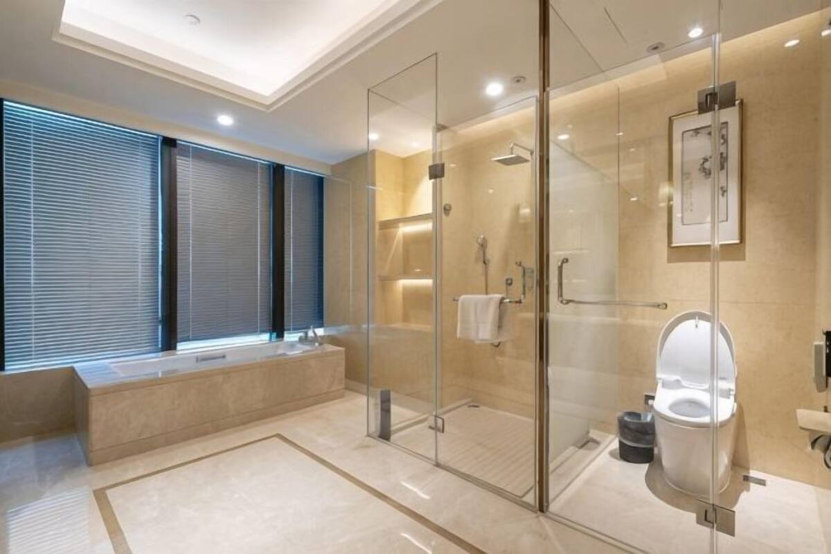 Un baño moderno con cabina de ducha de vidrio, inodoro y banco.