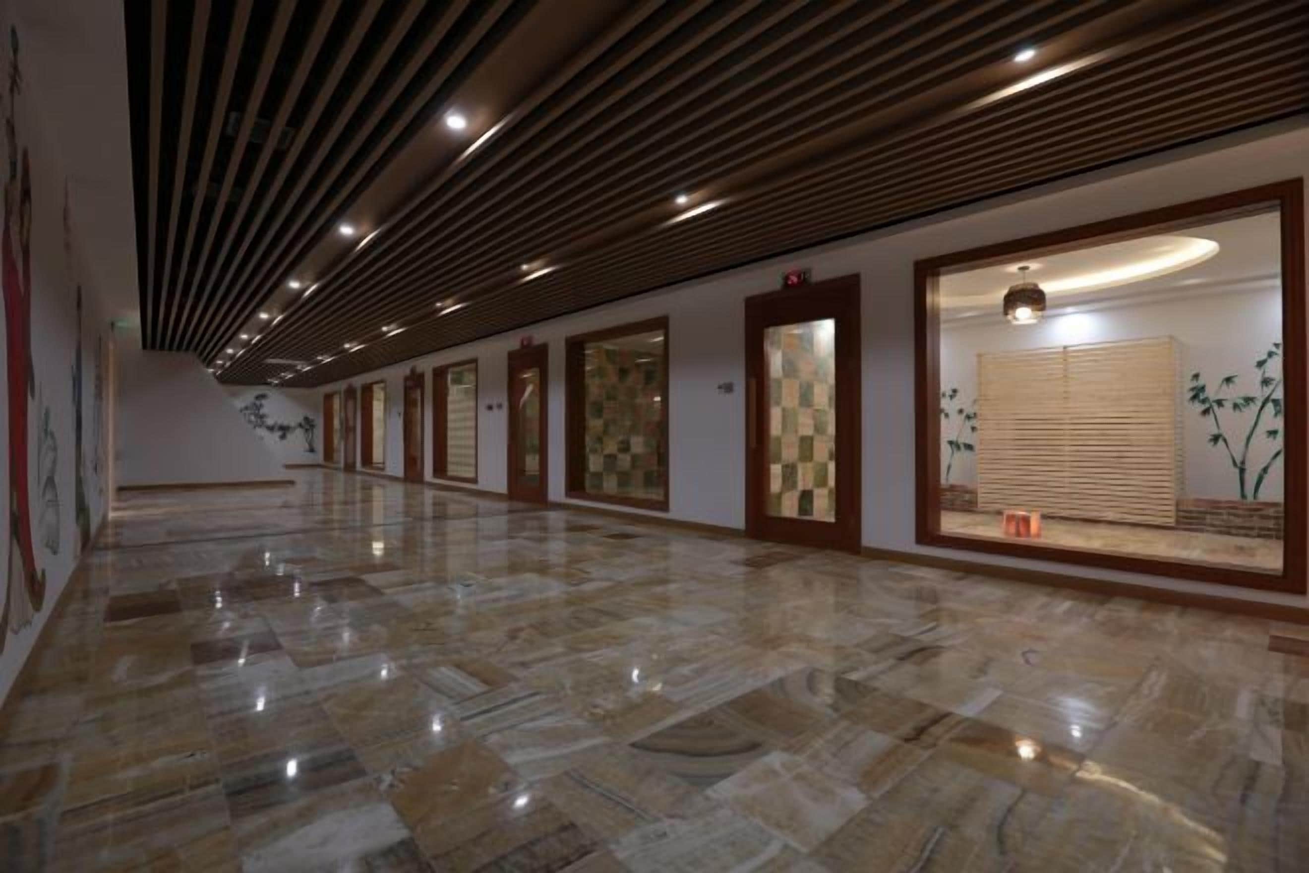 A hallway with a polished marble floor, wooden panel ceiling, and framed artwork on the walls.
