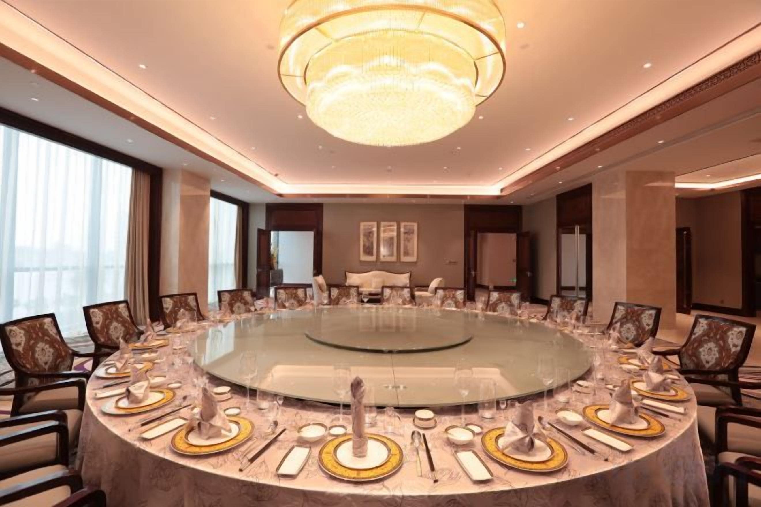 A conference room with a round table, chairs, and a chandelier.