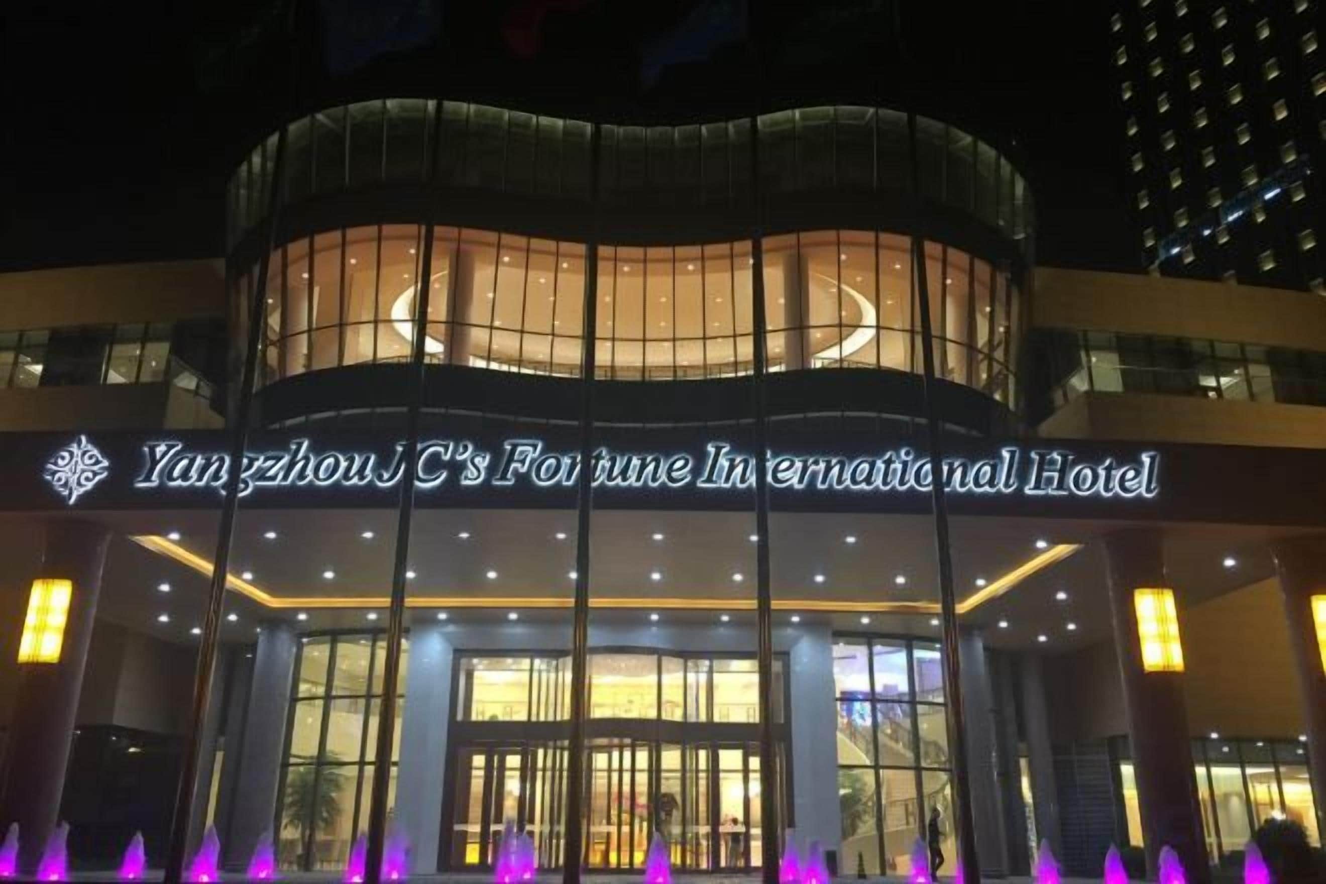 El exterior del Fortune International Hotel de Yangzhou J.C., con señalización iluminada y un diseño arquitectónico moderno.