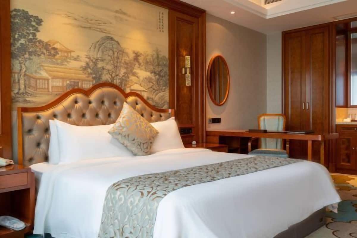 Habitación de hotel con una cama grande, un cabecero de madera, un escritorio y un armario.