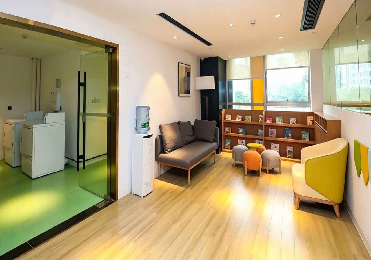 Un interior modern amb un sofà, cadires, una prestatgeria i una zona de cuina.