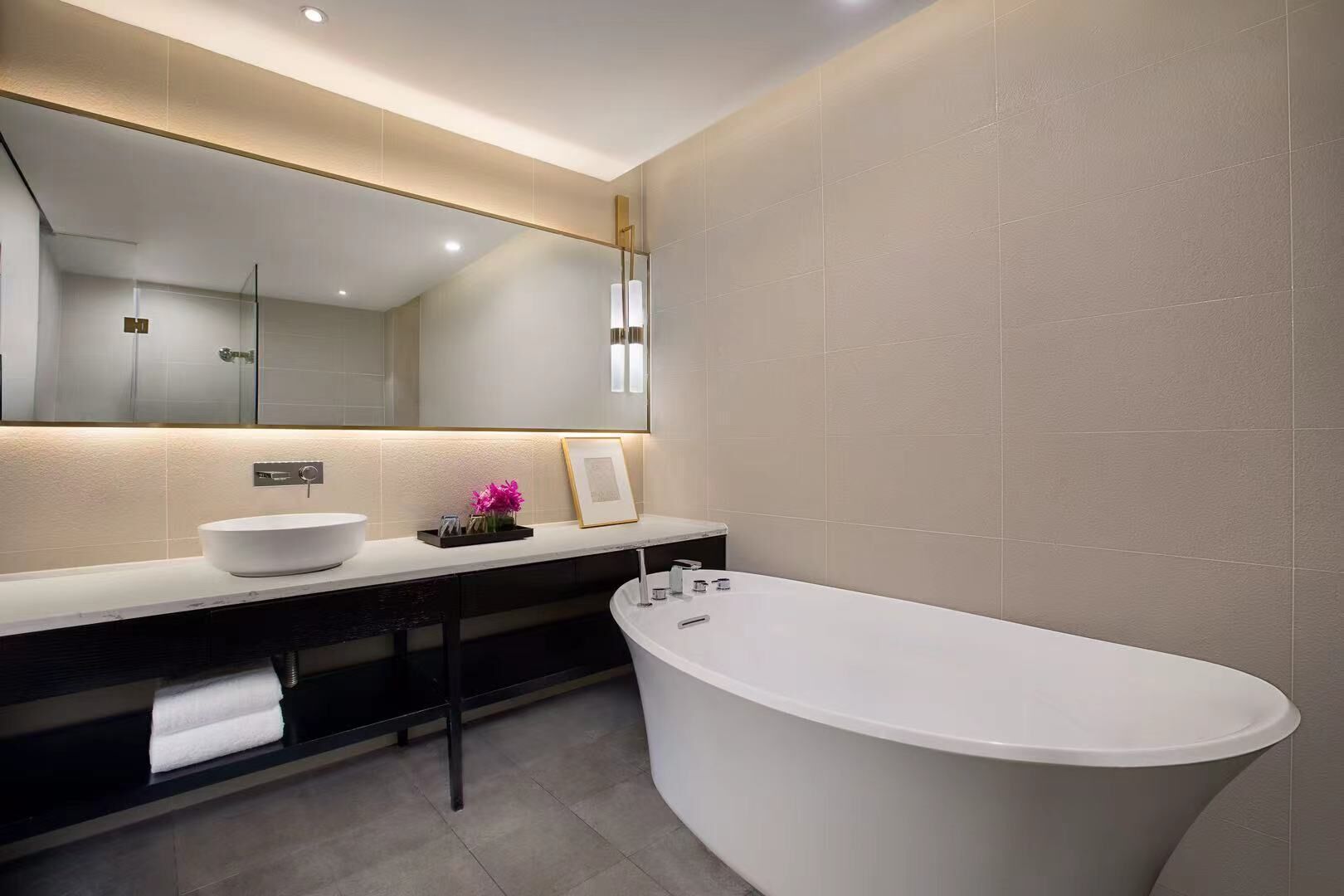 A modern bathroom with a freestanding bathtub, a large mirror, and a white sink.