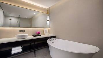A modern bathroom with a freestanding bathtub, a large mirror, and a white sink.