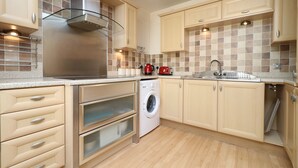 Una cocina moderna con electrodomésticos integrados, armarios de madera y salpicadero de azulejos.