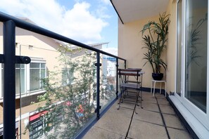 A balcony with a potted plant, a small table, and a chair. - 3 Bed Apartment - Mermaid Quay (Cardiff)